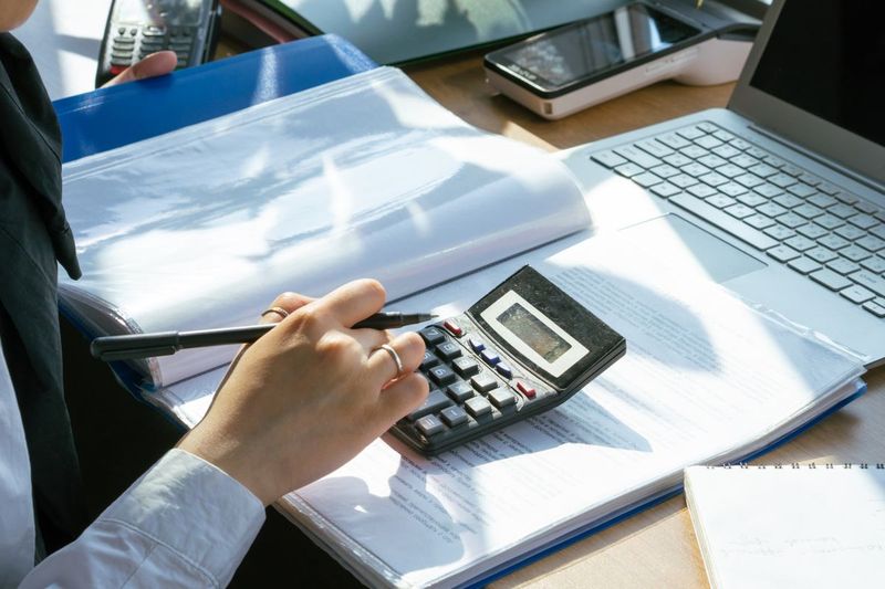 Healthcare finance professional reviewing reimbursement figures with a calculator and financial documents
